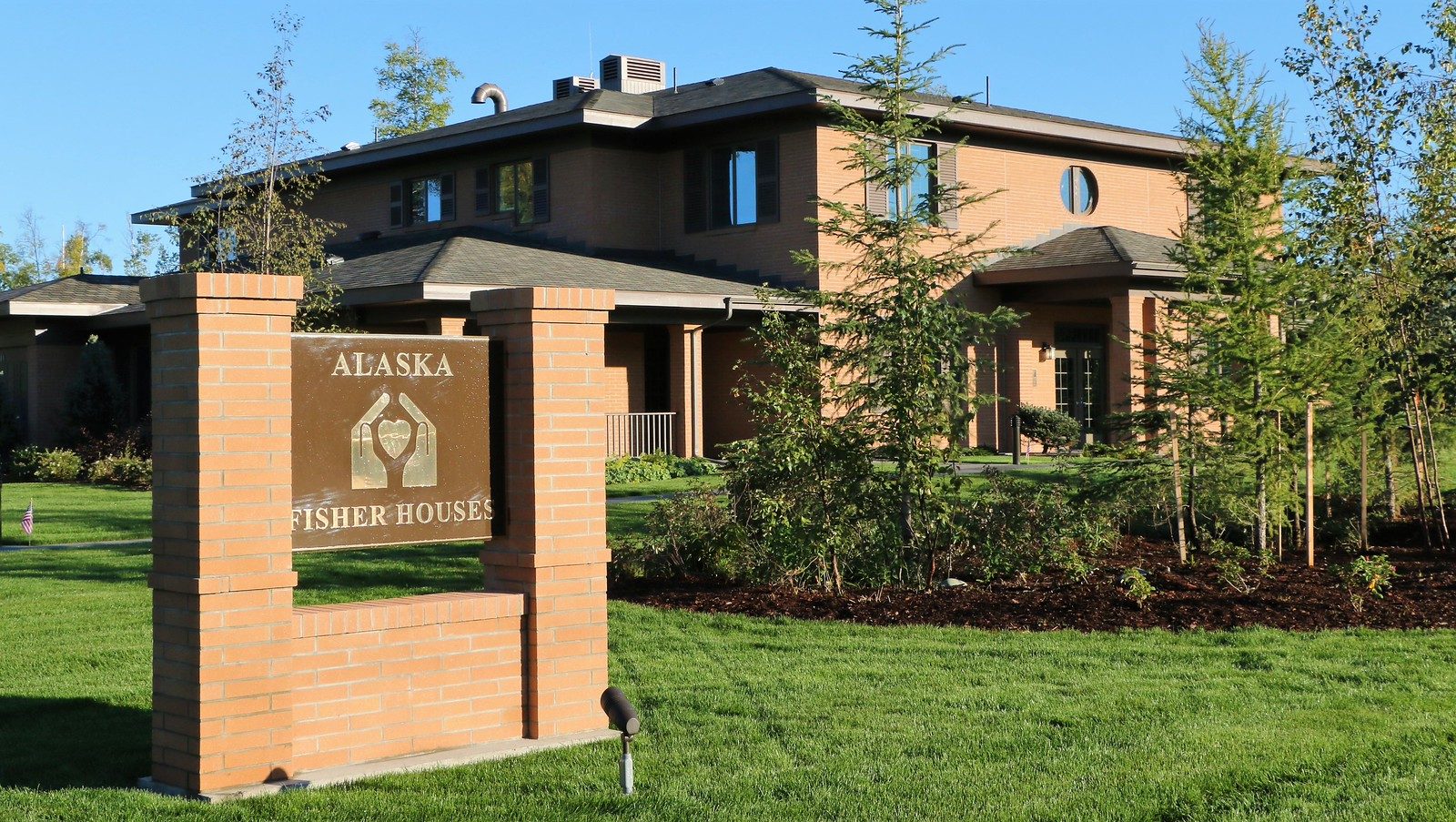 The Alaska Fisher House entrance sign and building on a summer day