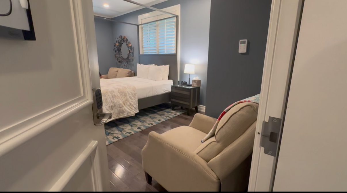 A private guest suite with a queen bed, armchair, and wreath on the wall