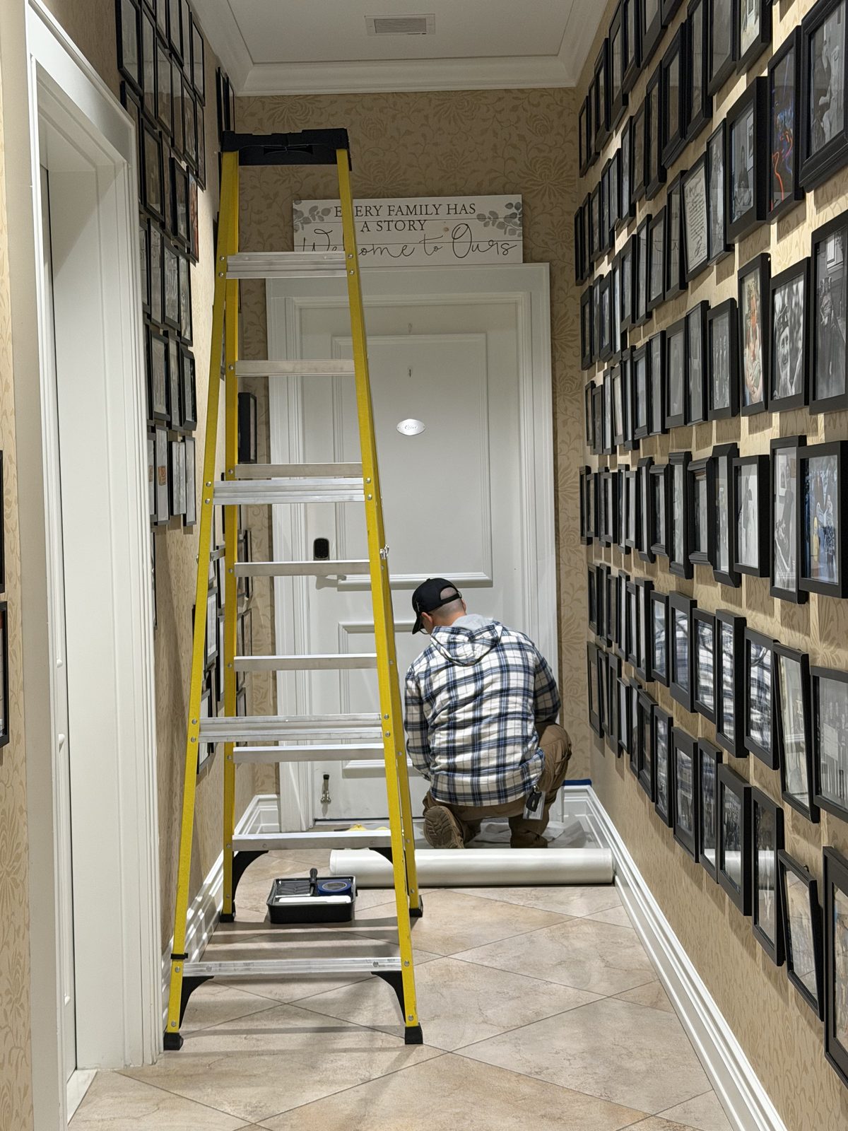A volunteer on a ladder painting a hallway inside the Fisher House