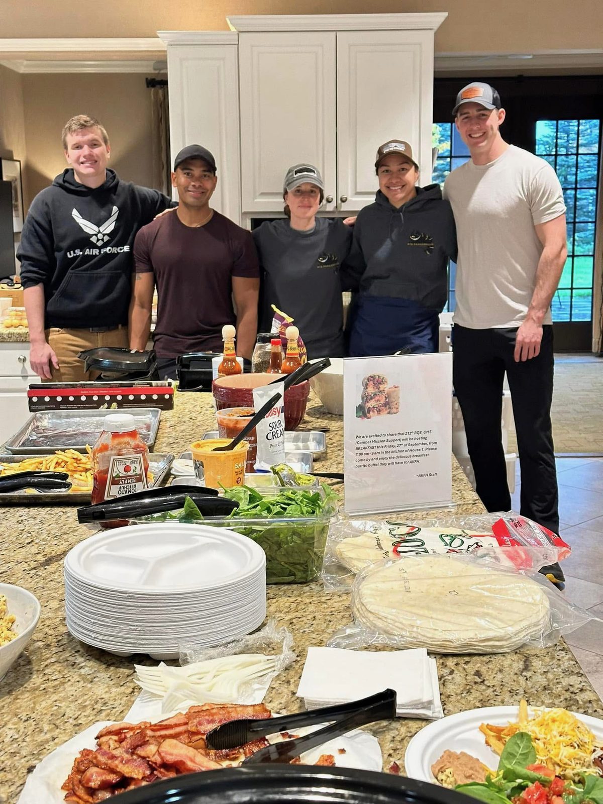 A group of volunteers serving a home-cooked meal in the Fisher House kitchen
